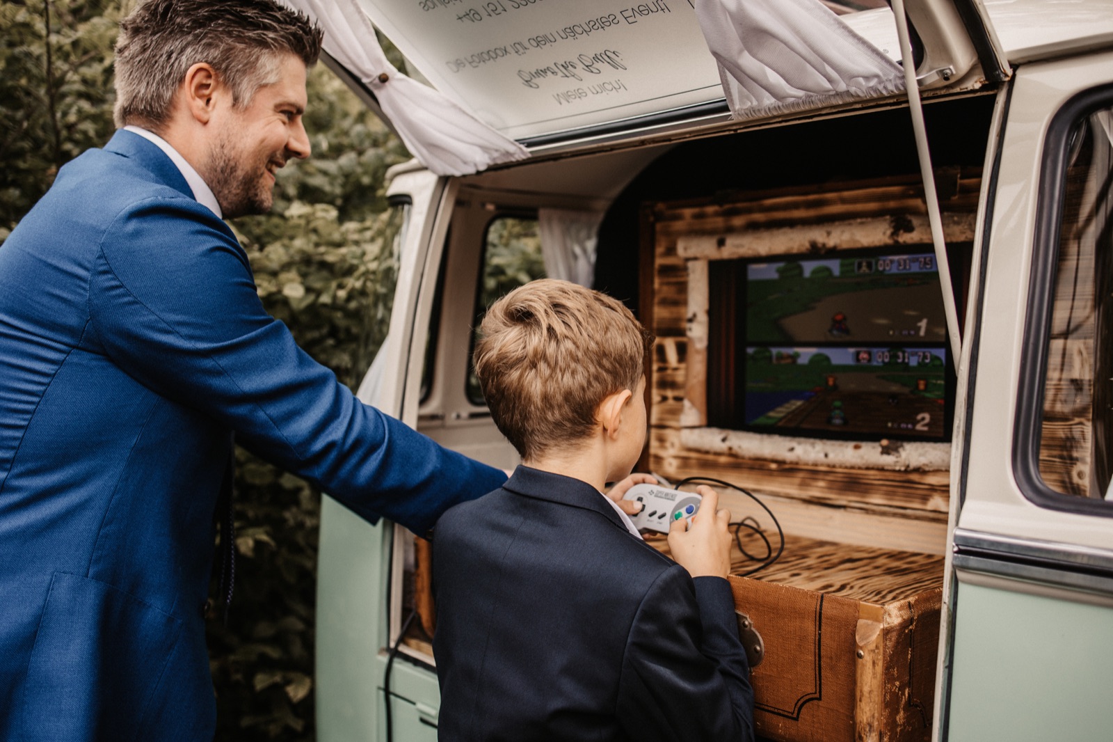 Vater und Sohn spielen an der Retro-Spielekonsole im Kofferraum